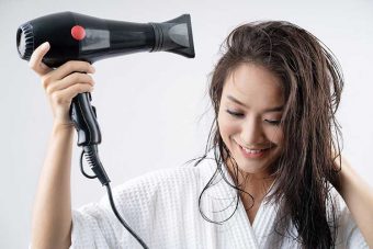 ドライヤーで髪を乾かす女性